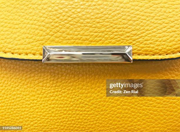 details of a vibrant yellow ladies handbag with silver colored metal decor on flap - yellow purse foto e immagini stock