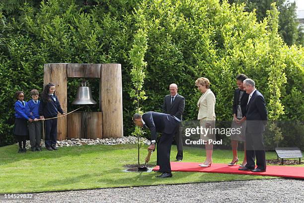 School children Onyedika Ukachukwu, Colm Dunne and Maragaret McDonagh hold the rope to the Peace Bell as U.S. President Barack Obama plants a tree...