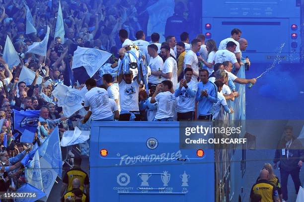 Manchester City's Spanish manager Pep Guardiola holds aloft the Premier League trophy to the fans as they take part in an open-top bus parade through...