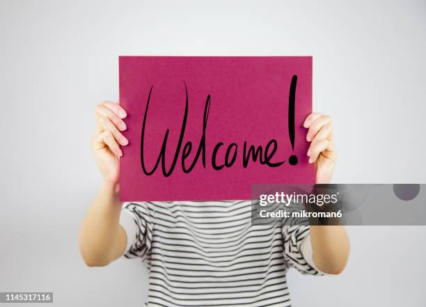 woman showing a paper page saying welcome - panneau de bienvenue photos et images de collection