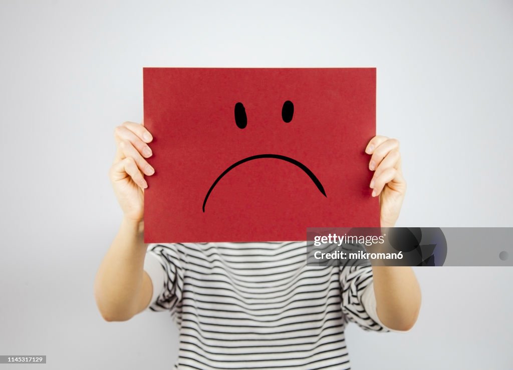 Woman showing a paper page with a sad face