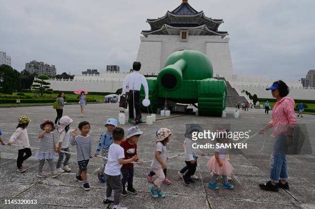 Children walk pass an artwork of Tank Man by Taiwanese artist Shake, inspired by a sketch of dissident Chinese artist Baidiucao, is on display in...