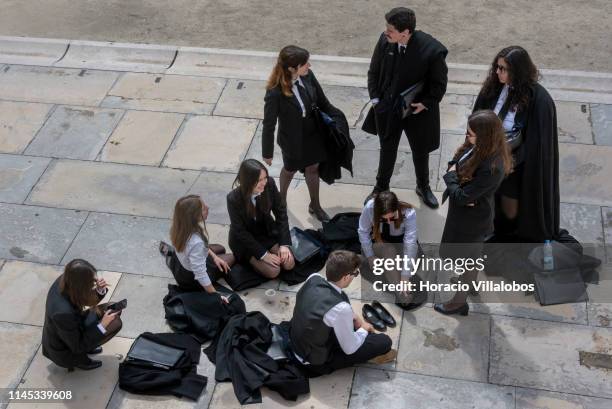 Group of University of Coimbra students wear black capes and traditional attire while waiting to pose for photographs outside the Royal Palace on...