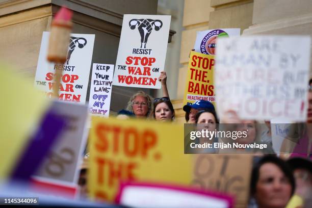 People hold signs during a protest against recently passed abortion ban bills at the Georgia State Capitol building, on May 21, 2019 in Atlanta,...