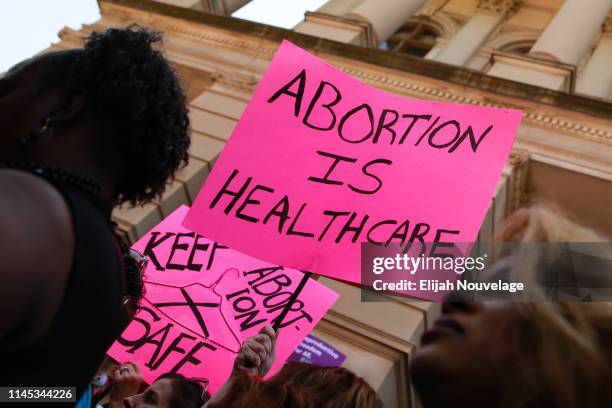 People hold signs during a protest against recently passed abortion ban bills at the Georgia State Capitol building, on May 21, 2019 in Atlanta,...