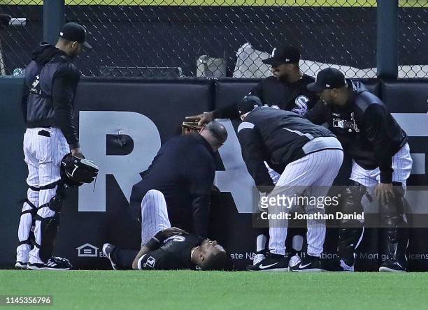 Eloy Jimenez of the Chicago White Sox is tended to after hitting the wall trying to catch a home run ball hit by Grayson Greiner of the Detroit...