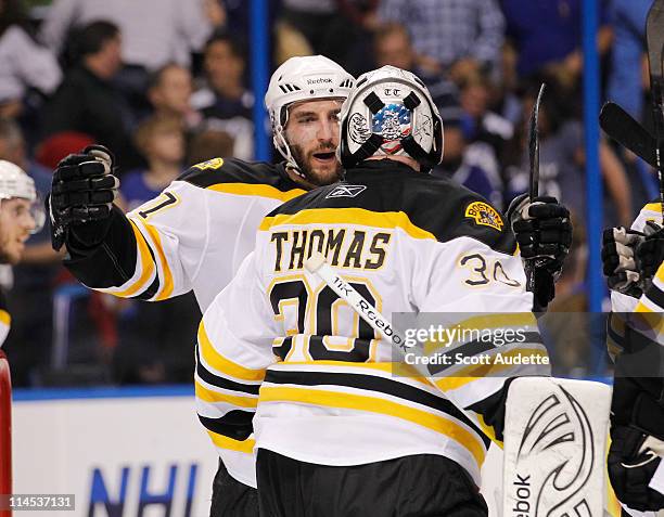 Patrice Bergeron of the Boston Bruins celebrates with teammate Tim Thomas after winning against the Tampa Bay Lightning in Game Three of the Eastern...