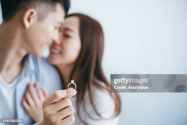 hombre con anillo de compromiso proponiendo matrimonio a la novia en la nueva casa, que se besan con la sonrisa - engagement fotografías e imágenes de stock