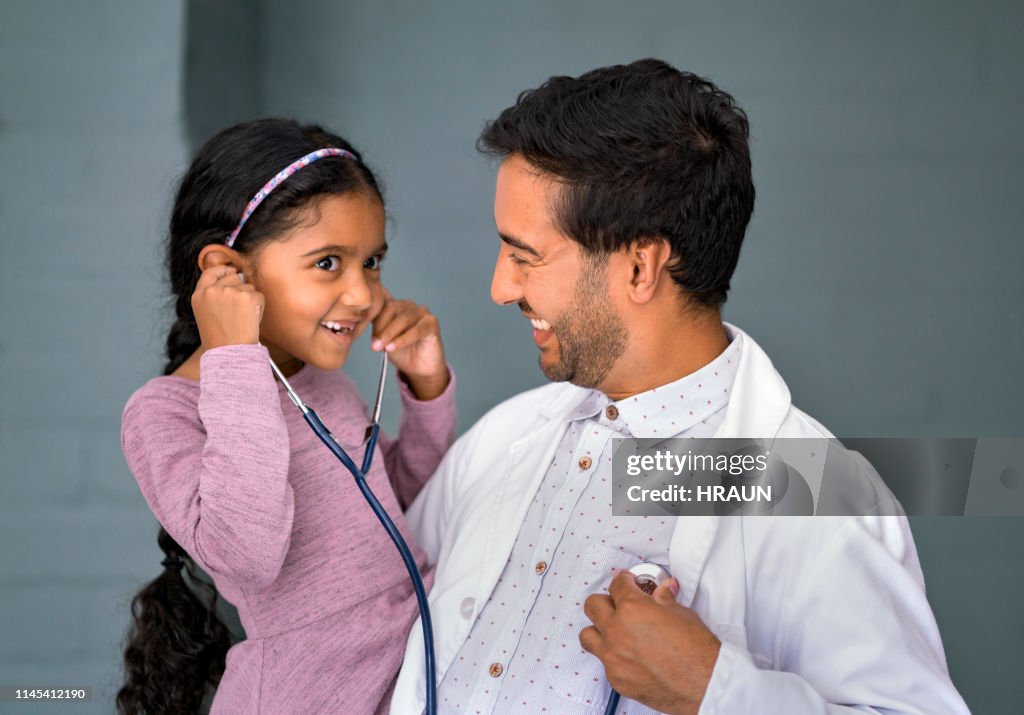 Smiling girl listening pediatrician's heartbeat