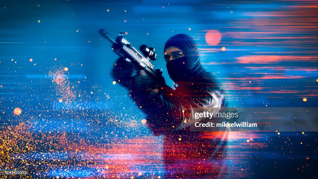 Soldier or criminal from video game holds a machine gun and aims at a target