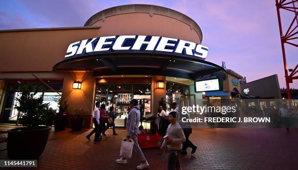 Shoppers at an outket mall walk past a Skechers store on May 21, 2019 in Los Angeles, California. - More than 170 shoe companies and retailers,...