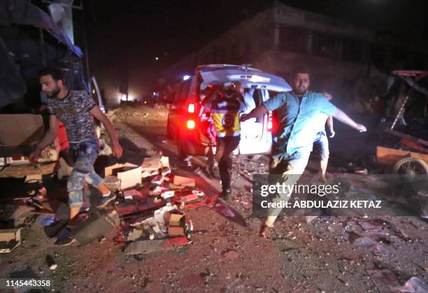 White Helmets rescue volunteers gather at the site of an air strike on a market in the town of Maaret al-Numan on May 21, 2019. At least 12 people...