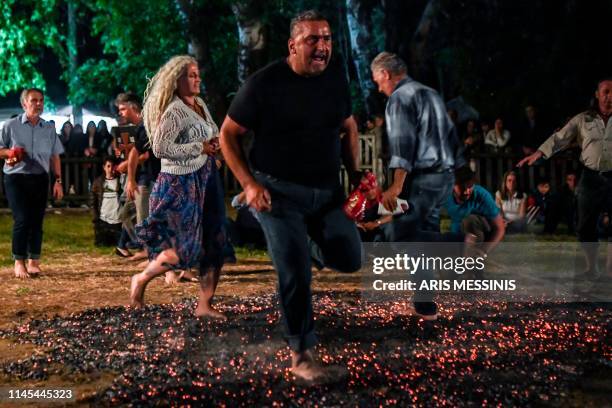 People walk on burning coals as they take part in the ancient tradition of Anastenaria, a fire-walking ritual, in the northern Greek village of...