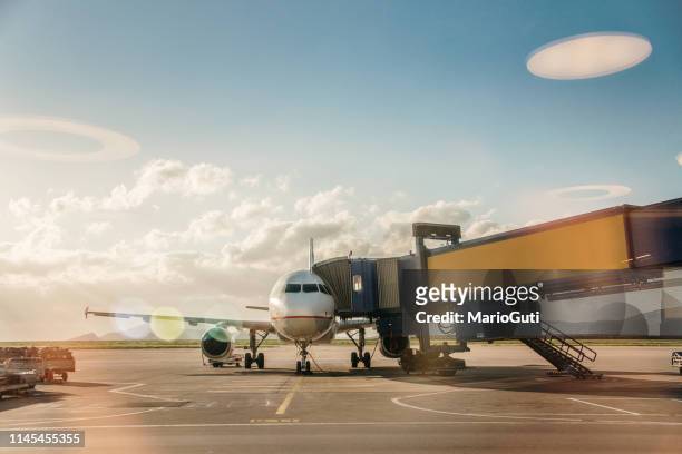 flugzeug in einem flughafen - passenger boarding bridge stock-fotos und bilder