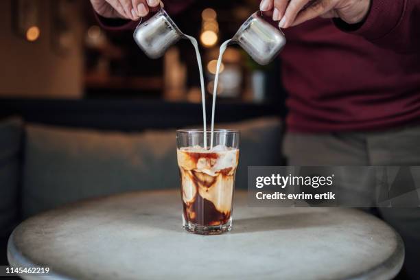 man pouring milk in iced coffee - spilling stock pictures, royalty-free photos & images