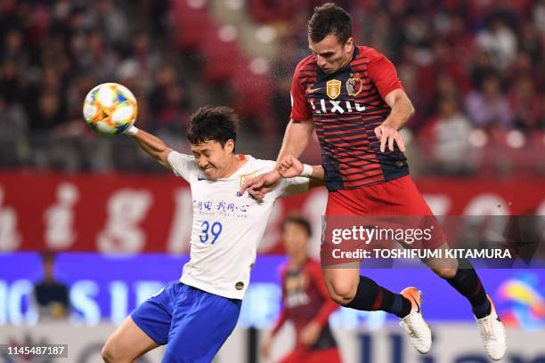 Shandong Luneng's Song Long fights for the ball with Kashima Antlers' Serginho during the AFC Champions League group E football match between Japan's...