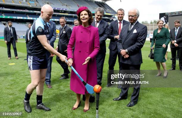 Sweden's King Carl XVI Gustaf watches as his wife Queen Silvia tries her hand at hurling, at Croke Park, the home of the Gaelic Athletic Association...