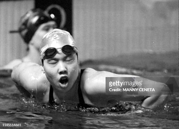 China's Zhong Weiyue holds on to the lane marker after breaking the world record in the 100 meter women's butterfly at the second leg of the 1994...