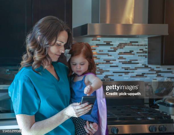 enfermera con hija en una capa jugando con el teléfono - cute nurses fotografías e imágenes de stock