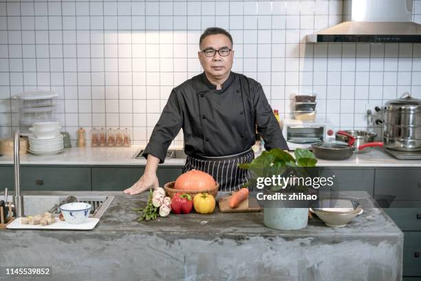 middle-aged chef preparing to cook in the kitchen - commercial kitchen and ingredients stock pictures, royalty-free photos & images