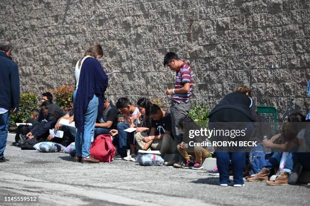 Volunteers assist Central American asylum seekers sitting outside the bus station in San Bernardino, California after they were brought their by U.S....