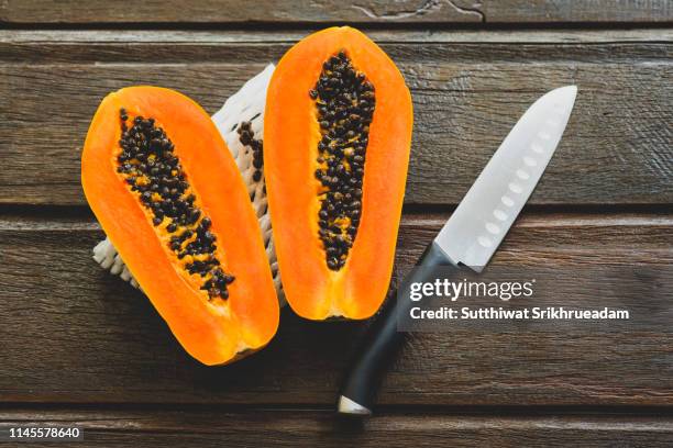 directly above shot of halved papayas and knife on wooden table - papaya stock pictures, royalty-free photos & images
