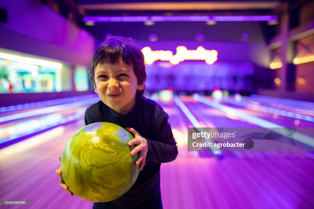 Criança bonito do retrato com a esfera no clube do bowling