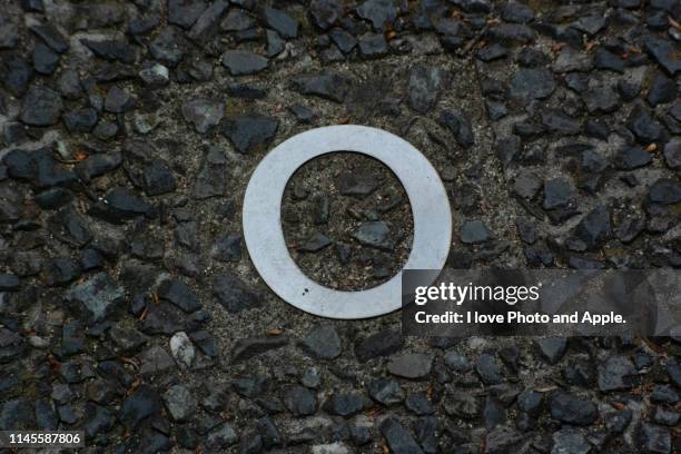 a small letter of the metal alphabet embedded in a road - o stockfoto's en -beelden