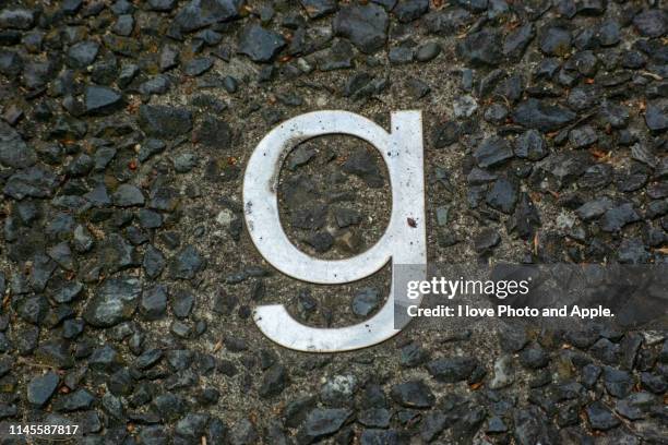 a small letter of the metal alphabet embedded in a road - as g stock pictures, royalty-free photos & images