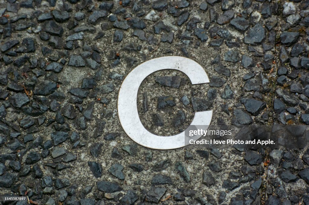A small letter of the metal alphabet embedded in a road