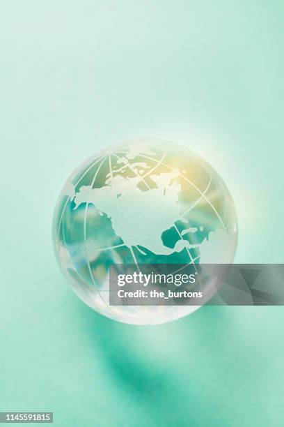 close-up of transparent globe on turquoise background - mundo de cristal fotografías e imágenes de stock