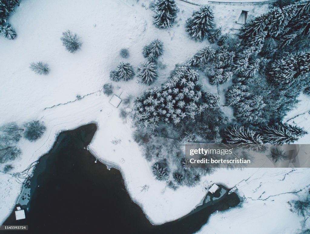 Aerial View Of Snow Covered Land By Lake During Winter