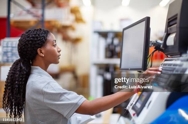 female worker working on a machine in factory - handhaben stock-fotos und bilder