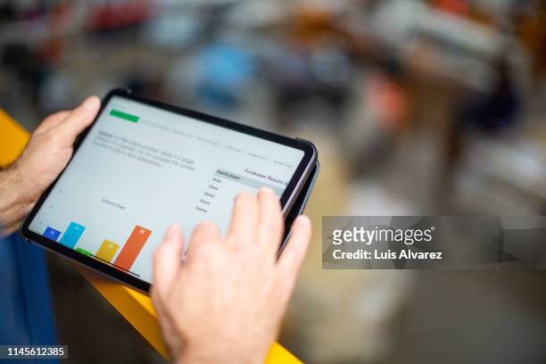 worker reviewing statistical graphs on tablet pc - ipad close up imagens e fotografias de stock
