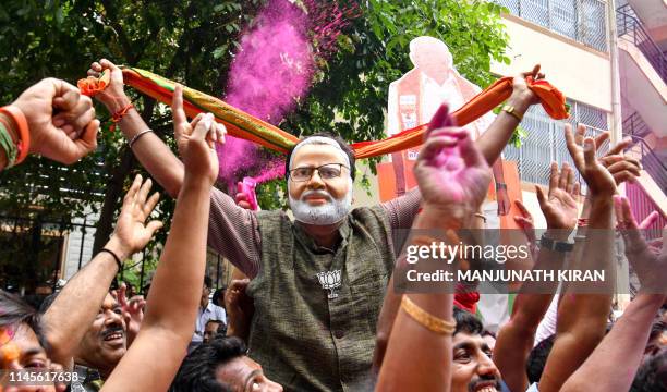 Supporter of Bharatiya Janata Party wearing a mask of Indian Prime Minister Narendra Modi dances as he celebrates on the vote results day for India's...