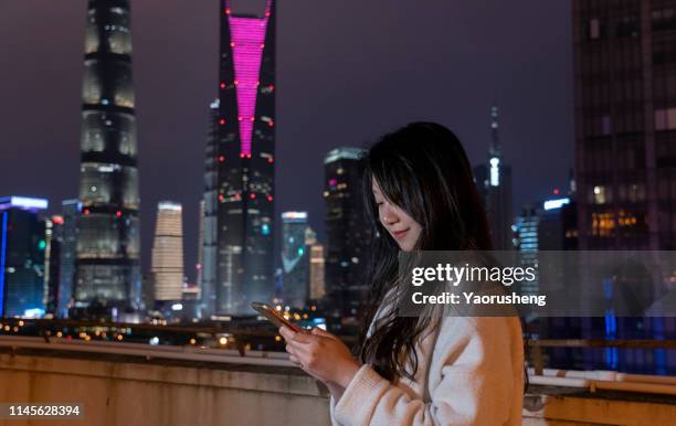 one asian charming  female using the mobile phone in the night city - shanghai calling stock pictures, royalty-free photos & images