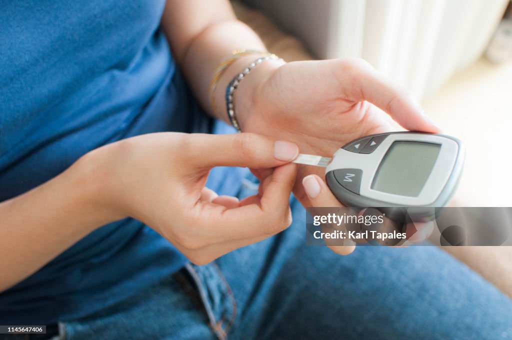 A young woman is using a glucometer