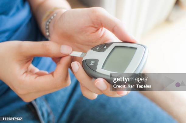 a young woman is using a glucometer - blood glucose stock pictures, royalty-free photos & images