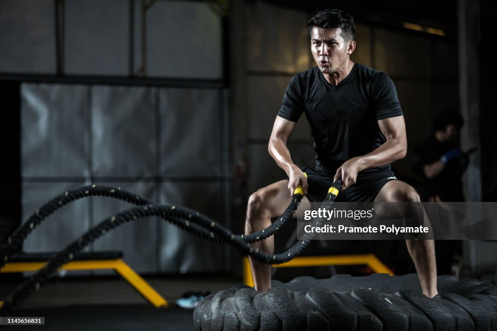 Asian man with battle rope battle ropes exercise in the fitness gym, exercises concept.