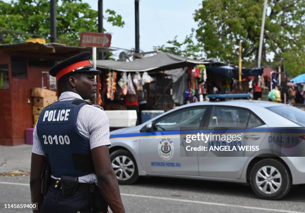 Jamaica Constabulary Force police officer stands guard in the Half Way Tree neighborhood in Kingston, Jamaica on May 18, 2019. - The JCF is the...