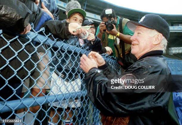 New York Yankees pitching coach and baseball great Whitey Ford signs autographs for fans after a wet practice 17 February 1994 in Miami, FL. The...