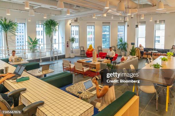 Members work in the cafeteria at the WeWork Cos Inc. 85 Broad Street offices in the Manhattan borough of New York, U.S., on Wednesday, May 22, 2019....