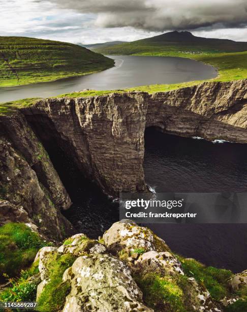 die färöer landschaft mit hohen klippe - optische illusion stock-fotos und bilder