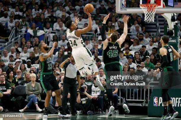 Giannis Antetokounmpo of the Milwaukee Bucks attempts a shot while being guarded by Marcus Morris and Aron Baynes of the Boston Celtics in the first...