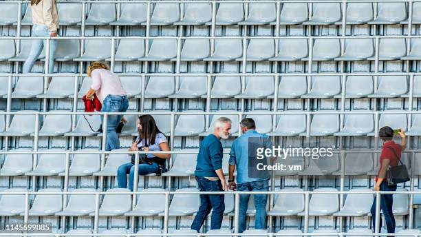 nur wenige menschen nehmen ihre plätze auf stadionblecher ein - small group of people stock-fotos und bilder