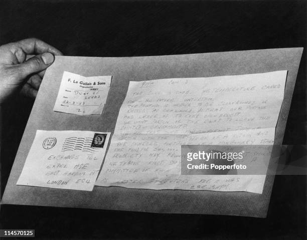 An assistant editor at the Exchange Telegraph news agency holds an anonymous letter, along with its envelope, postmarked Lancaster and Morecambe, and...