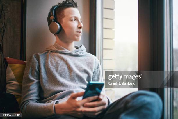 teenager listening to music in headphones - boy headphones imagens e fotografias de stock