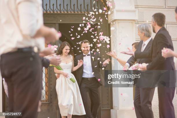 guests throwing rose petals on bride and groom - leaving church stock pictures, royalty-free photos & images