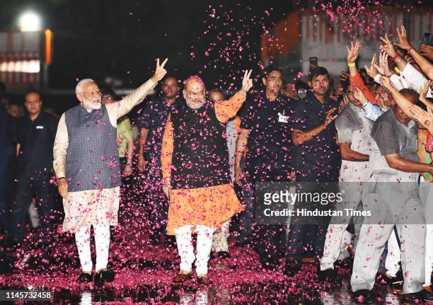 Prime Minister Narendra Modi shows victory sign as he, along with the party President Amit Shah, arrives at the party headquarters to celebrate their...