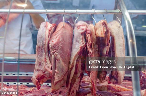 pieces of raw red meat hanged in the butcher's - slaughterhouse stock-fotos und bilder